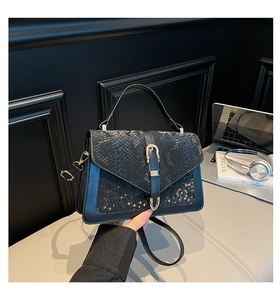 Close-up of black snake pattern flap bag with golden horseshoe buckle on a desk