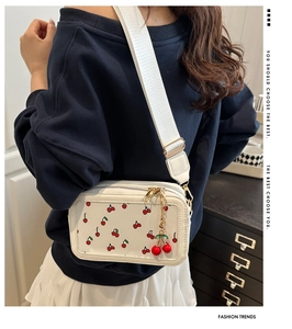 Detail of crossbody bag with cherry pattern and adjustable wide fabric strap