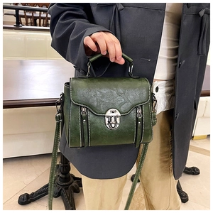 Detailed shot of dark green vintage PU leather bag with white stitching and metal clasp