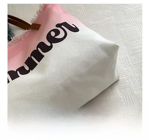 Detail of pink gradient canvas tote bag featuring summer text and fringe edges