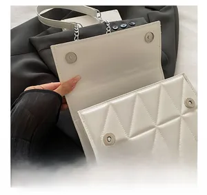 Détails du sac matelassé blanc montrant les fermoirs magnétiques et la bandoulière chaîne