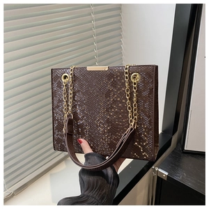 Detail of brown faux snake skin leather texture with golden metal buckle and chain strap