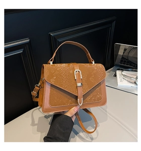 Detail of brown snakeskin embossed handbag featuring a polished silver metal buckle closure