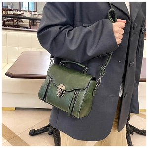 Detail view of vintage forest green crossbody bag with side zipper trim and flap closure