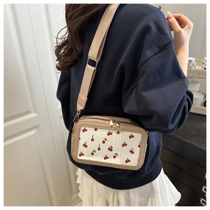 On-body view of square crossbody bag with cherry pattern and wide adjustable strap