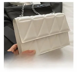 Détail du sac matelassé blanc avec motif géométrique et bandoulière en chaîne argentée