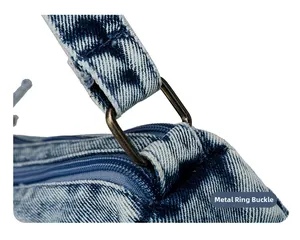 Detail of blue denim shoulder bag showing bronze hardware rings and stitching texture
