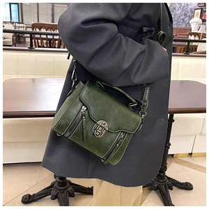 Detail of green vintage oil wax leather crossbody bag with wave flap and metal lock