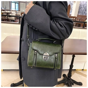 Detail of green leather crossbody bag with vintage metal lock and contrast stitching