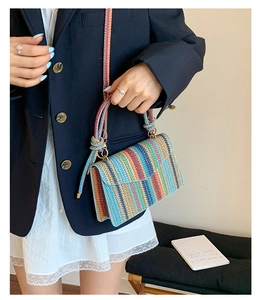 Detail shot of multi-color striped straw woven crossbody bag with decorative rope knots