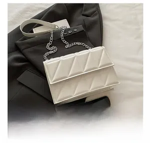 Gros plan d'un mini sac bandoulière blanc matelassé avec chaîne argentée à côté d'un smartphone