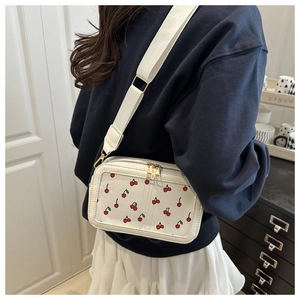 Detail of white crossbody bag featuring cherry print, clear window, and wide strap