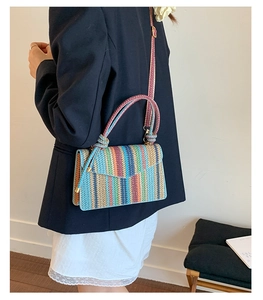 Detail of colorful striped woven straw bag with adjustable shoulder strap for women