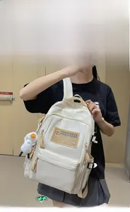 Detail view of white nylon backpack featuring multiple pockets and a small duck plush charm