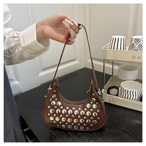 Detail of a brown crescent hobo bag with silver rivets and sleek leather shoulder strap