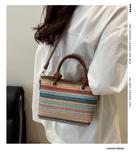 Détail d'un sac en paille à rayures colorées avec anse en cuir marron et œillets dorés