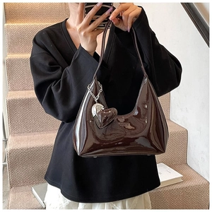 Detail of dark brown patent leather hobo bag featuring a metallic heart-shaped charm