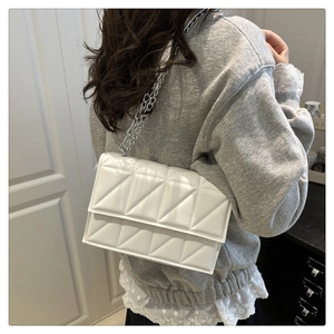 Détail d'un sac blanc matelassé avec motif géométrique 3D et bandoulière en chaîne argent