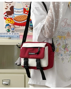 Detail of red and white messenger bag with DUOMAN logo and black buckle closure