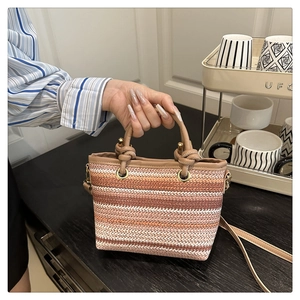 Détail du sac seau tissé main avec rayures orange et poignée en cuir marron