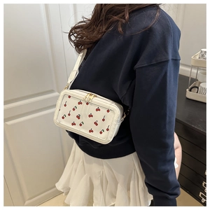 Detailed back view of a white cherry print crossbody bag with adjustable shoulder strap