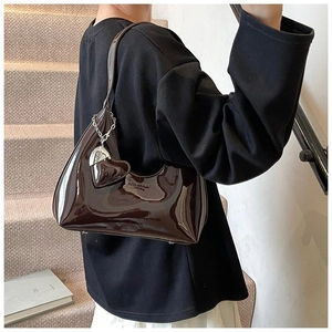 Detail of burgundy patent leather baguette bag with silver chain and heart charm