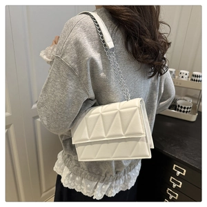 Détail du sac bandoulière blanc avec matelassage géométrique et bandoulière en chaîne