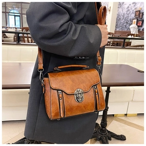Detailed close-up of brown oil-wax leather messenger bag with vintage metal buckle