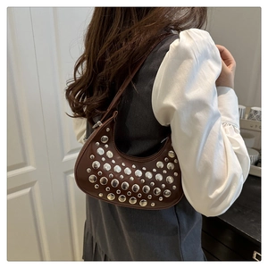 Detail of dark brown crescent bag featuring silver rivet studs and a slim leather shoulder strap