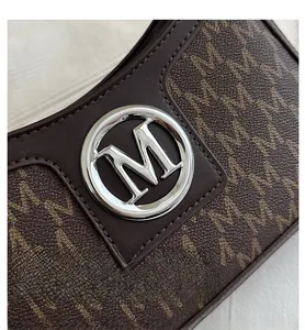 Close-up of the vintage silver M-buckle and monogram pattern on brown leather bag