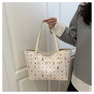 Detail of cartoon print tote bag with metal rivets and leather brand patch on ivory fabric