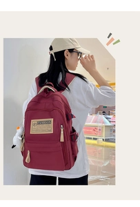 Detail of burgundy waterproof nylon backpack with white goose plush charm and side buckle