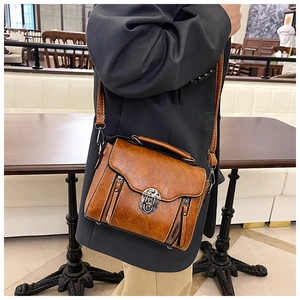 Close-up of vintage brown PU leather crossbody bag with metal buckle and zipper detail