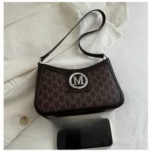 Brown monogram underarm bag detail showing size comparison with a smartphone