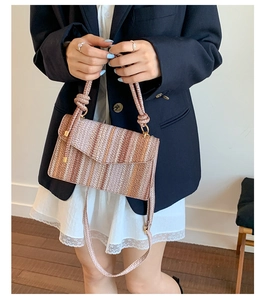 Close-up of a woven striped crossbody bag featuring pink and brown patterns