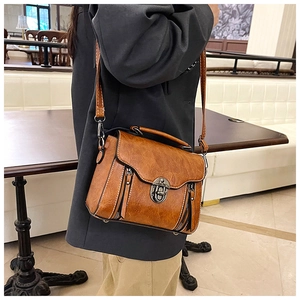Detail view of brown vintage leather crossbody bag with metallic turn-lock and zipper accents