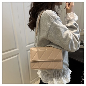 Détail d'un sac bandoulière matelassé beige avec chaîne en argent sur un modèle