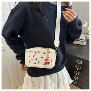 White cherry pattern crossbody bag styled with white skirt and wide shoulder strap