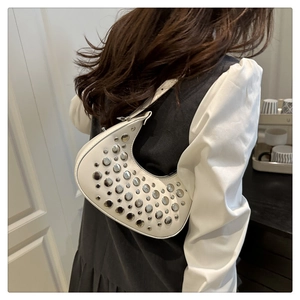 Detail shot of white crescent hobo bag featuring stylish silver rivets and shoulder wear