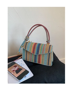 Detail view of colorful rainbow striped straw woven handbag with metallic gold hardware