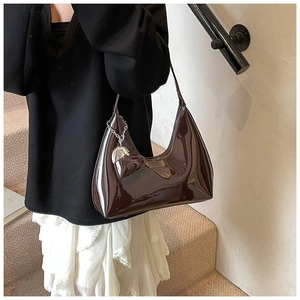 Detail view of dark brown glossy patent leather hobo bag with silver heart chain charm