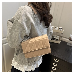 Détail du sac bandoulière matelassé abricot avec chaîne argentée et broderies triangulaires