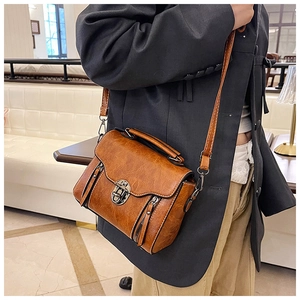 Close-up of retro brown crossbody bag with metal buckle and decorative dual zippers