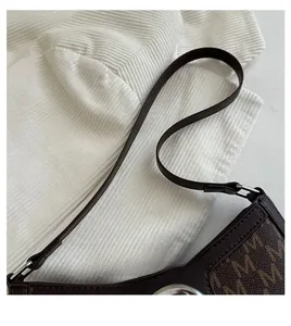 Detail of vintage underarm bag featuring letter print patterns and leather shoulder strap