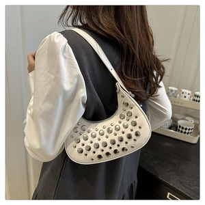Detailed view of white half-moon hobo bag featuring silver rivets and slim shoulder strap