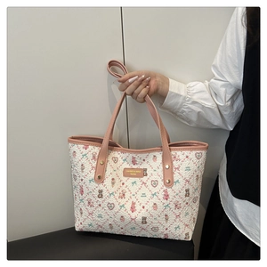 Close-up of cute cartoon pattern tote bag with pink leather handles and gold rivets