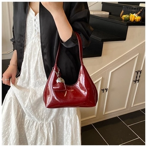 Detail of a dark red patent leather hobo bag with high gloss finish and heart charm