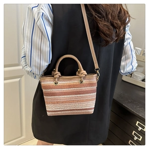Détails du sac seau en paille tressée avec rayures et accessoires en métal doré