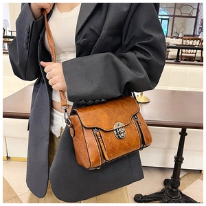 Close-up of vintage brown leather crossbody bag with wave flap and metal buckle detail