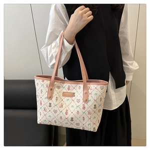Detail of printed tote bag with pink bear patterns and leather handles in a home setting